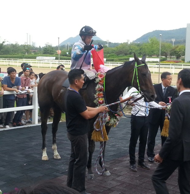 El Padrino and David Flores fly the flag in the Winner's Circle